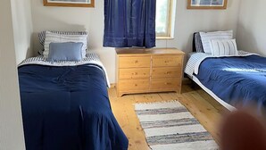 Un dormitorio con dos camas, un aparador de madera y dos cuadros en las paredes.