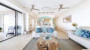 A modern living room with a white sofa, a glass coffee table, and a large window. - ZEN POINT PENTHOUSE - 3 BR Waterfront (Darwin)