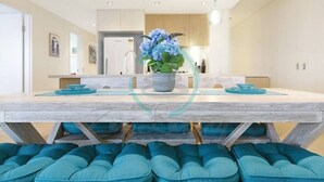 A modern kitchen with a central island, a potted plant, and teal cushions on the seating area. - ZEN POINT PENTHOUSE - 3 BR Waterfront (Darwin)