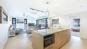 A modern kitchen with a central island, a dining area with a view, and a living room with a sofa and a coffee table. - ZEN POINT PENTHOUSE - 3 BR Waterfront (Darwin)