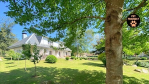 Een huis met een verzorgd gazon en een grote boom op de voorgrond.
