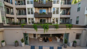 A multi-story building with a central courtyard featuring outdoor seating and planters. - 1 bd Apt in Marina Del Rey - Venice. Resort style complex with premium amenities (Marina del Rey)