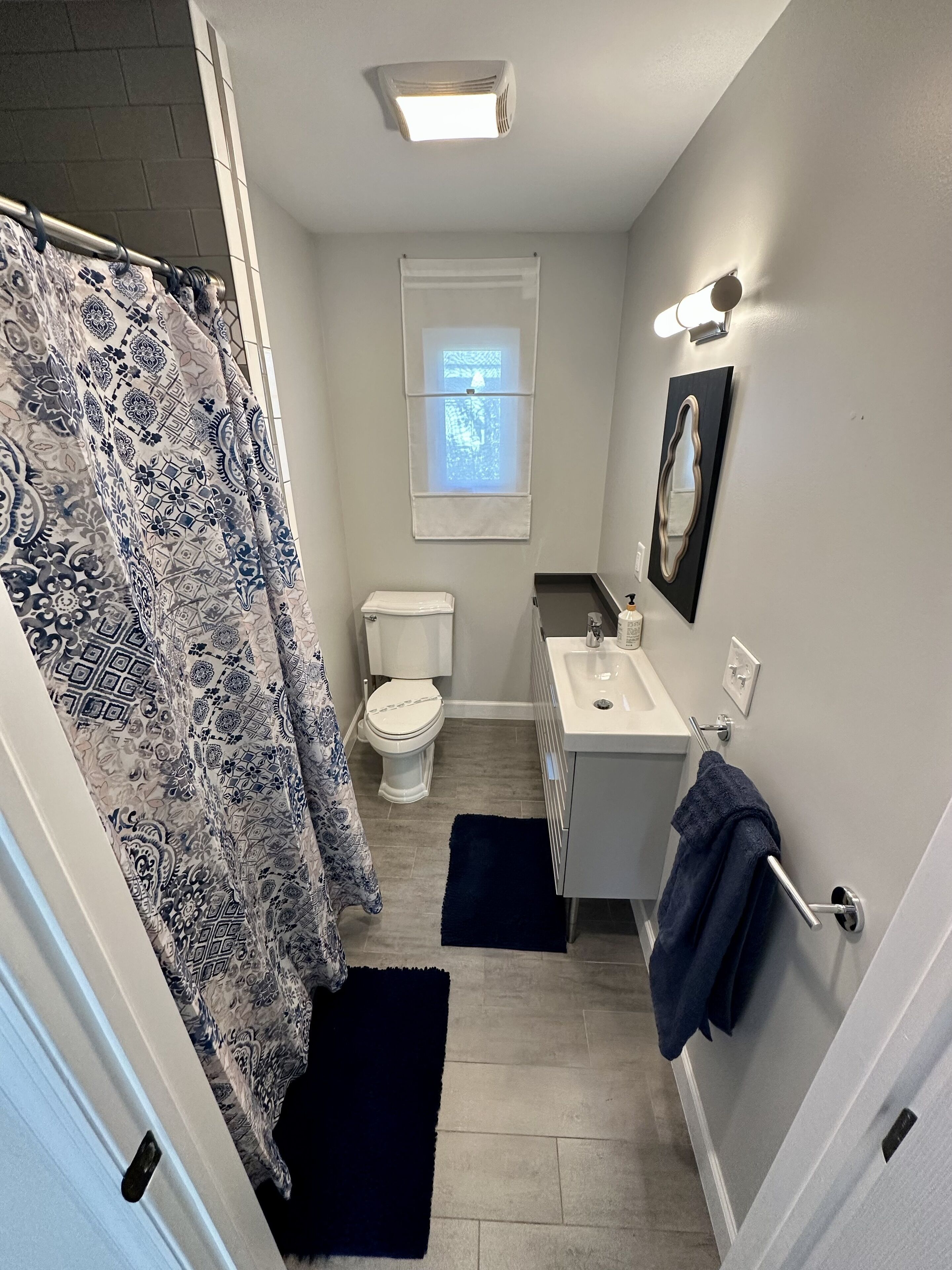 Une salle de bain avec un rideau de douche, des toilettes, un lavabo et une fenêtre.