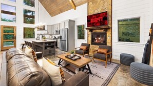 A spacious living area with a fireplace, a stone accent wall, and a large TV. - ✨Hampton's Hideaway: Luxury cabin with 🎲 Games, 🪁 Playground, and 💦 Hot Tub✨ (Broken Bow)
