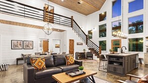 A spacious living room with a leather sofa, wooden coffee table, and a staircase leading to an upper level. - ✨Hampton's Hideaway: Luxury cabin with 🎲 Games, 🪁 Playground, and 💦 Hot Tub✨ (Broken Bow)