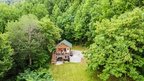 A cabin with a porch, surrounded by dense forest. - RELAX - HOT TUB & GORGEOUS MOUNTAIN VIEWS                                    (Amherst)