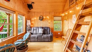 A cozy cabin interior with a sofa, chairs, a wooden staircase, and a wreath on the wall. - RELAX - HOT TUB & GORGEOUS MOUNTAIN VIEWS                                    (Amherst)