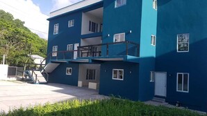 A multi-story building with balconies and a staircase leading to the entrance. - Stylish modern apt beach view (Belmont)