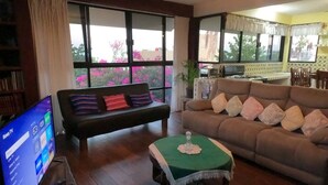 Ein Wohnzimmer mit einer Couch, einem kleinen Tisch und einem Fernseher, der eine Speisekarte für den Zimmerservice zeigt.