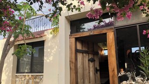 Ein Haus mit Holztür, Steinmauer und einem Balkon mit rosa Blumen.