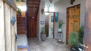 Eine Holztretreppe führt zu einer zweiten Etage, eine Tür mit Spiegel und ein Blumentopf auf dem Boden.