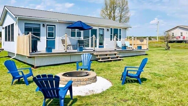 Ein Haus mit überdachter Veranda, Sitzgelegenheiten im Freien und einem Feuerkorb.