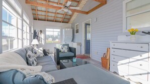 Ein gemütliches Zimmer mit einer Couch, einem kleinen Tisch, einer Kommode und einem Deckenventilator.