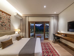 Relax in a spacious room with a large bed, desk, and flat-screen TV, offering a view of the outdoors.