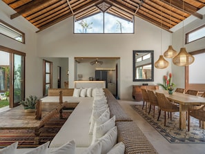 Relax in this airy space with a sofa, dining area, and kitchen, offering a view of the outdoors.