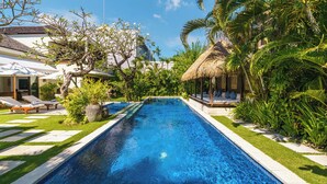 Ein Pool mit Liegestühlen und einer Struktur mit Reetdach.