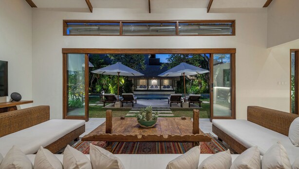 Ein modernes Wohnzimmer mit einem großen Glasfenster, das auf eine Terrassenanlage im Freien führt.