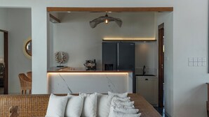 Ein modernes Schlafzimmer mit einem großen Bett, einem eingebauten Schreibtisch, einer Kaffeemaschine und einem Kühlschrank.