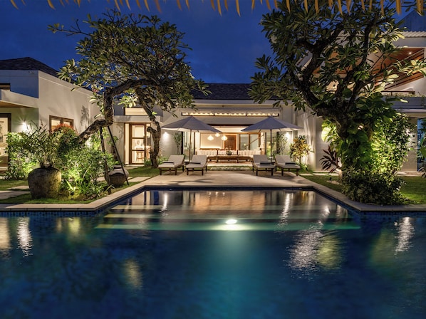 Relax in a serene outdoor setting surrounded by lush greenery and modern furniture.