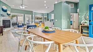 Un salón espacioso con una mesa de comedor de madera, sillas blancas, un sofá azul y una chimenea.