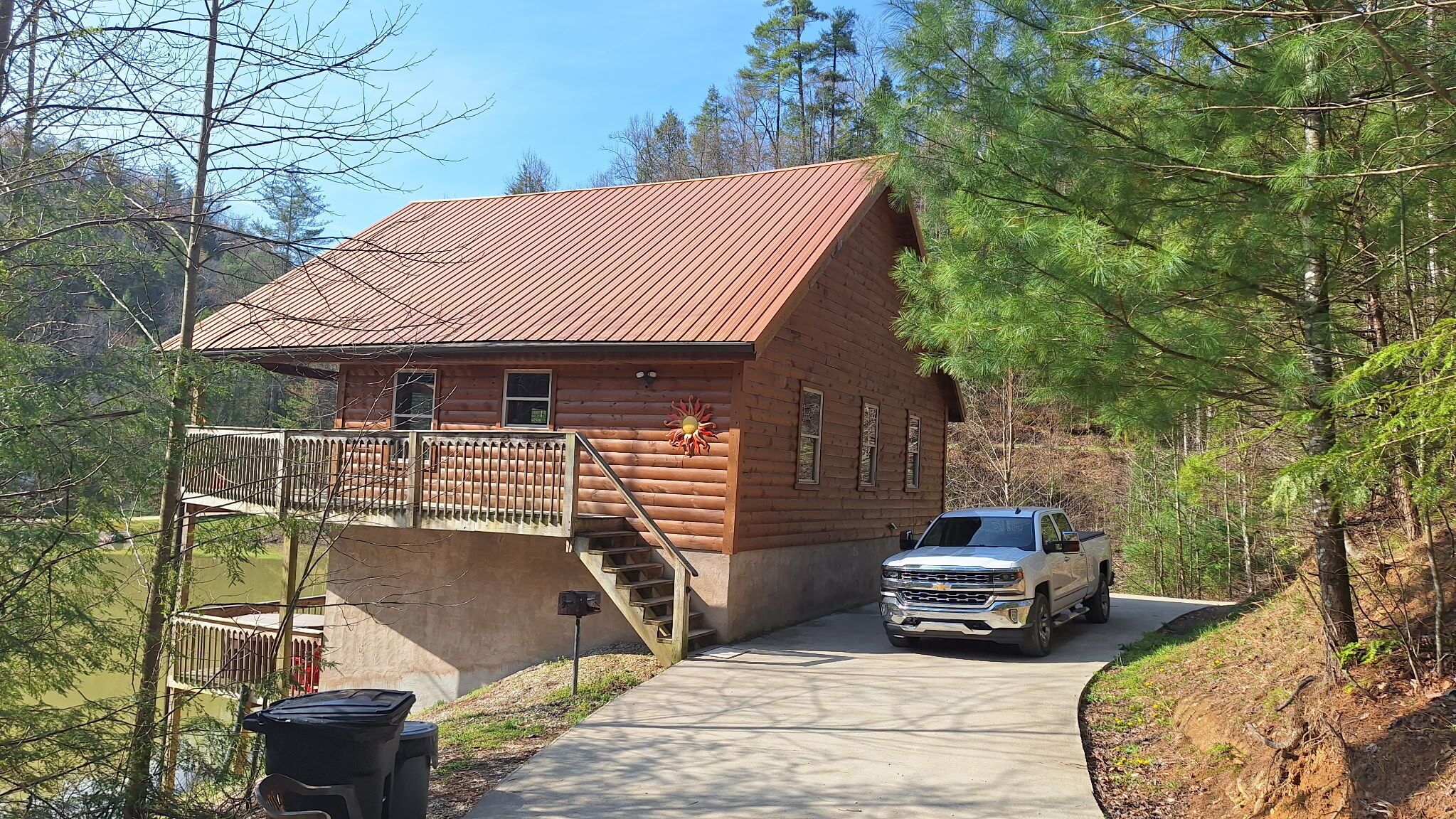 A log cabin with a metal roof, a porch, and a staircase leading to the entrance.