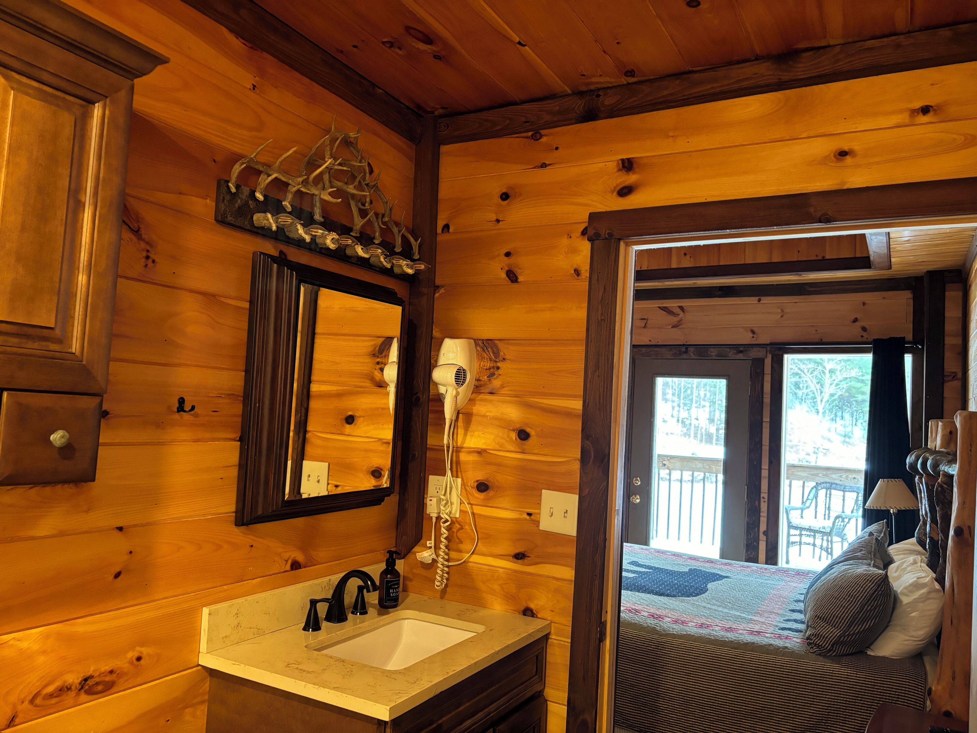 Een houten cabin met een badkamer, inclusief wastafel, spiegel en haardroger.
