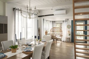 Enjoy meals in this spacious dining area with a long table, high ceiling, and large window.