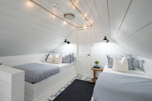 Two beds with matching bedding, each with a bedside table and lamp, are positioned in this cozy space.
