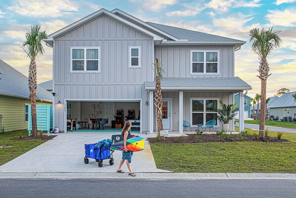 A two-story house with a garage, a covered porch, and a well-maintained lawn. - FullyLoaded5BR~Walk2Pool&Beach~Gameroom~Firepit~Sleeps16 (Port St. Joe)