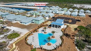 An aerial view of a coastal resort with multiple buildings, a central pool, and a parking area. - FullyLoaded5BR~Walk2Pool&Beach~Gameroom~Firepit~Sleeps16 (Port St. Joe)