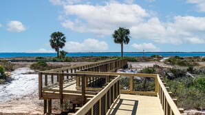 A wooden boardwalk leading to a beach with palm trees and a clear blue sky. - FullyLoaded5BR~Walk2Pool&Beach~Gameroom~Firepit~Sleeps16 (Port St. Joe)
