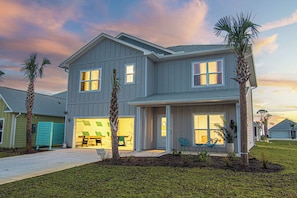 A two-story house with a garage, a covered patio, and a well-maintained lawn.