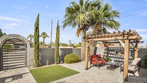 Eine Terrasse mit einer Pergola, Sitzgelegenheiten im Freien und einer Feuerstelle.