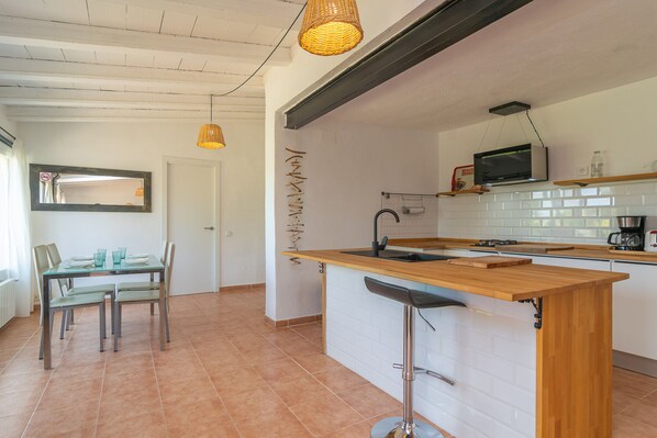 A modern kitchen with a wooden island, white tiled backsplash, and a built-in microwave.