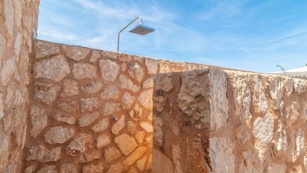 A stone wall with a metal structure on top, possibly a light fixture.