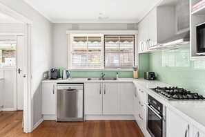A modern kitchen with stainless steel appliances, a dishwasher, a sink, and a window with blinds. - Flanders  Pet-friendly near Hampton Village (Hampton)