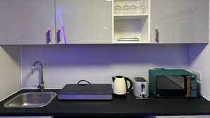 A modern kitchen with a built-in microwave, kettle, toaster, and a sink.
