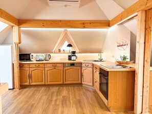 A kitchen with wooden cabinets, a microwave, toaster, coffee maker, and a sink. - Maisonette Wohnung mit Dachterasse (Dresden)