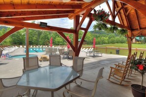 Ein überdachter Außenbereich mit Pool, Liegestühlen und einem Tisch.