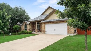A two-story house with a stone facade, a garage, and a well-maintained lawn.