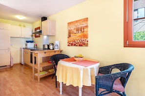 A compact kitchen with a dining area, a painting on the wall, and a window with a view.