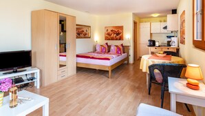 A bedroom with a bed, a TV, a desk, and a dining area. - Holiday Apartment "Hach" with Private Terrace & Wi-Fi (Sulzburg)