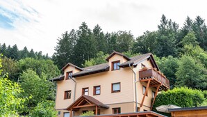 A multi-story building with a sloped roof, wooden balconies, and a view of a forested hillside. - Holiday Apartment "Hach" with Private Terrace & Wi-Fi (Sulzburg)
