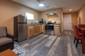 A compact kitchen with a refrigerator, microwave, oven, and wooden cabinets. - Far West RV Park and Cabins (Forks)