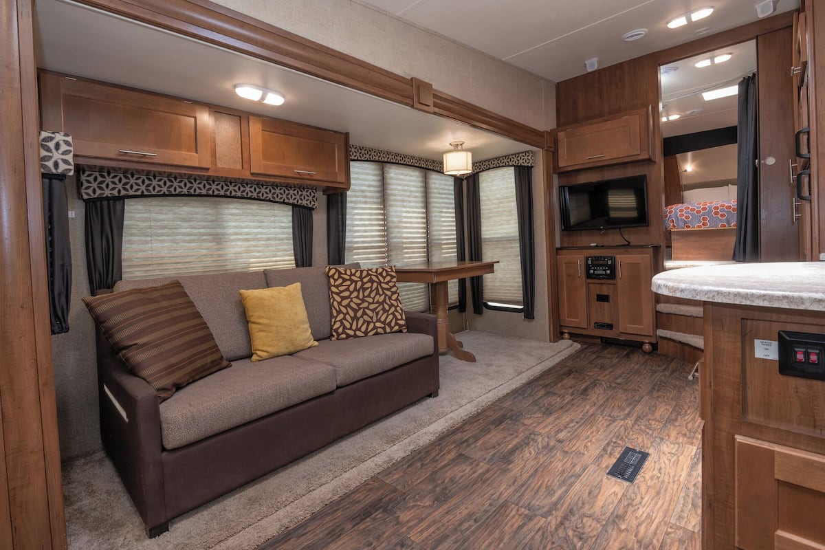 A cozy RV interior with a sofa, a table, and a TV.