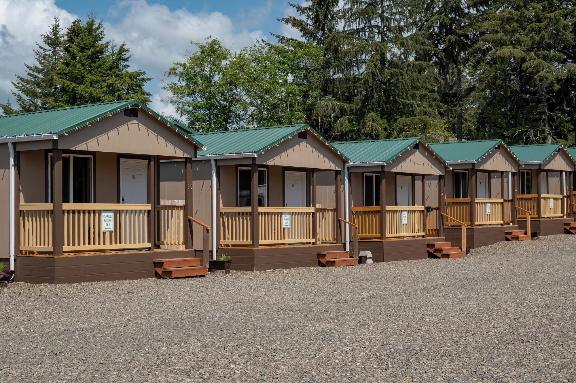 Une rangée de cabanes dotées de terrasses en bois et un sol recouvert de gravier.