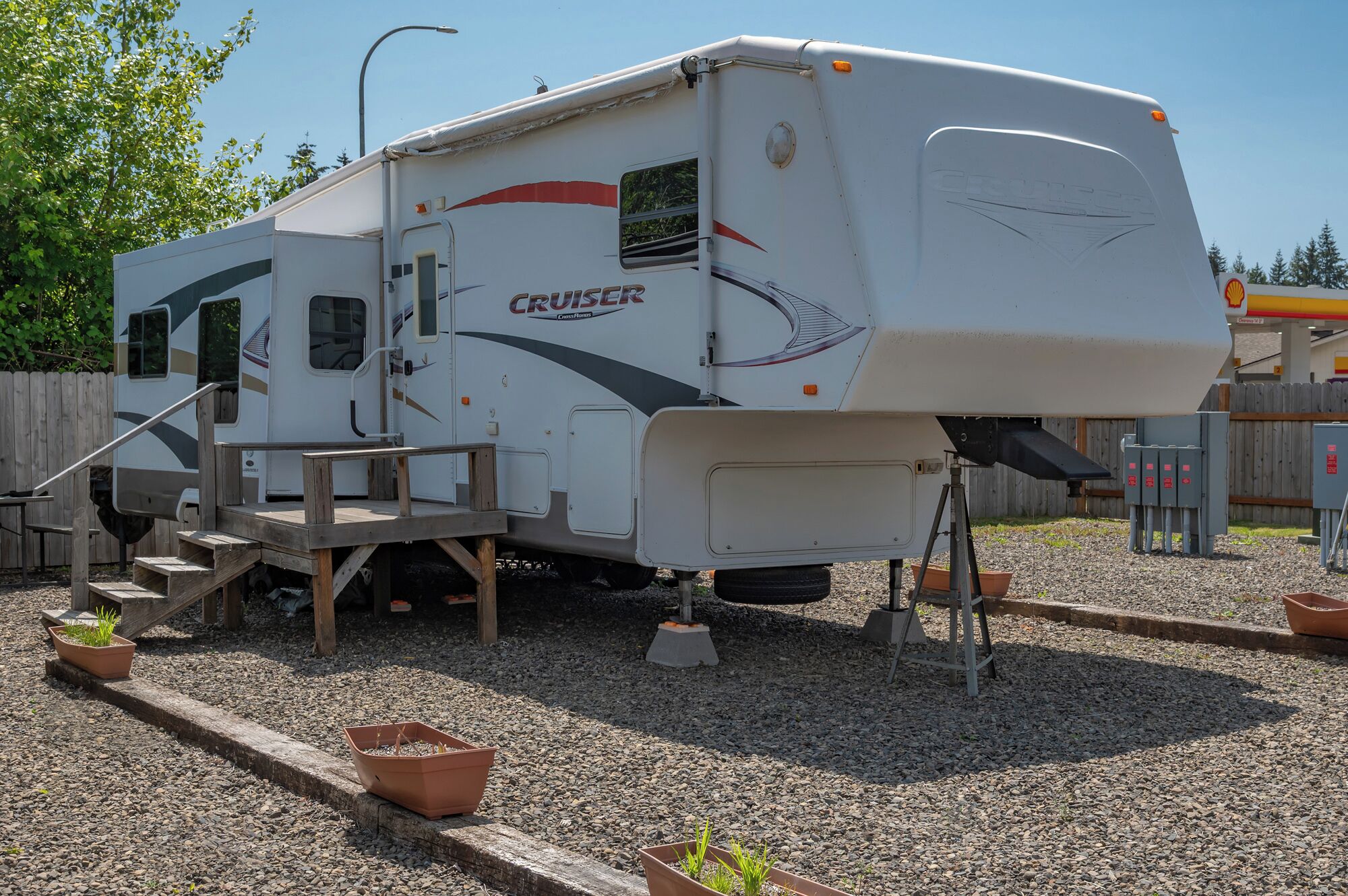 Una caravana blanca con el logo 'Cruiser', equipada con un pequeño porche y escalones.