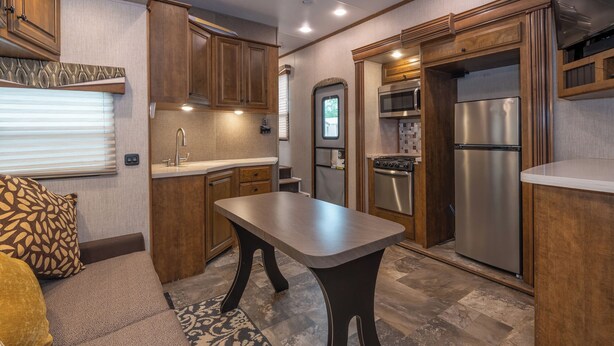 A compact kitchen with wooden cabinets, a stainless steel refrigerator, a microwave, and a stove. - Far West RV Park and Cabins (Forks)