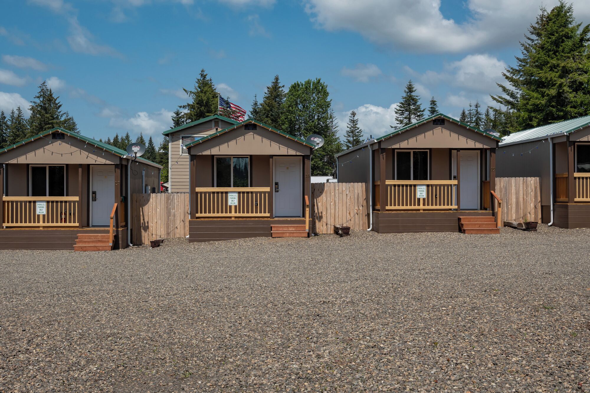 A row of small, single-story cabins with wooden railings and a gravel ground.
