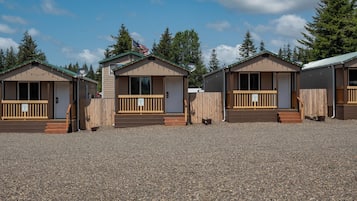 A row of small, single-story cabins with wooden railings and a gravel ground.